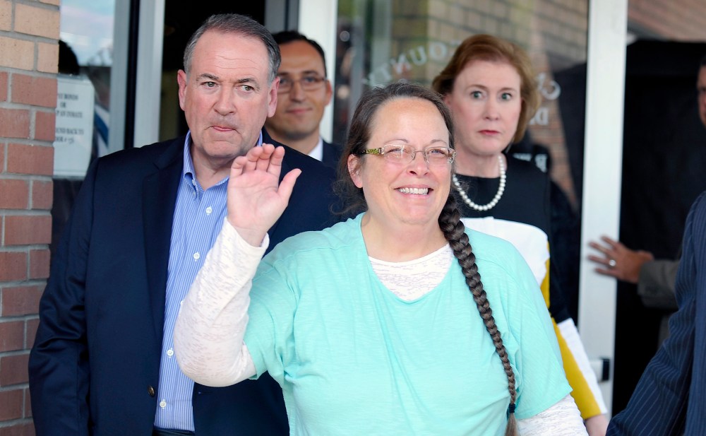 Kim Davis, flanked by Republic presidential candidate Mike Huckabee waves as she walks out of jail, Sep. 8, 2015. (Photo by Chris Tilley/Reuters)