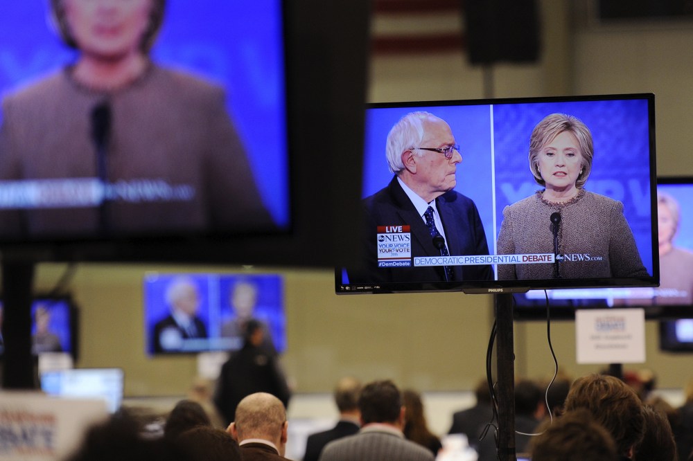 Democratic presidential candidates Hillary Clinton and Bernie Sanders appear on screens in the media room during the debate held at Saint Anselm College in Manchester, N.H., Dec. 19, 2015. (Photo by Gretchen Ertl/Reuters)