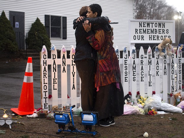 Newtown residents embrace after observing a moment of silence outside a firehouse nearby Sandy Hook Elementary in Newtown, Connecticut