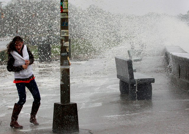 A woman reacts to waves crashing over a seawall in Narragansett, R.I., Monday, Oct. 29, 2012.  Hurricane Sandy continued on its path Monday, as the storm forced the shutdown of mass transit, schools and financial markets, sending coastal residents...