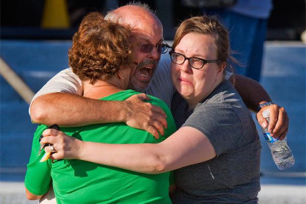 Tom Sullivan embracing family members outside Gateway High School. He has been frantically searching  for his son, Alex Sullivan, who celebrated his 27th birthday by going to see 