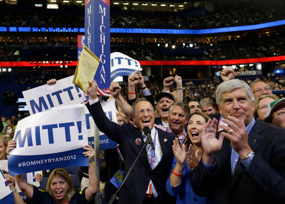 Michigan delegate Scott Romney, center with a note pad, and the rest of Michigan delegates react at the Republican National Convention in Tampa, Fla., on Tuesday, Aug. 28, 2012. At right is Michigan Gov. Rick Snyder. (AP Photo/Charles Dharapak)