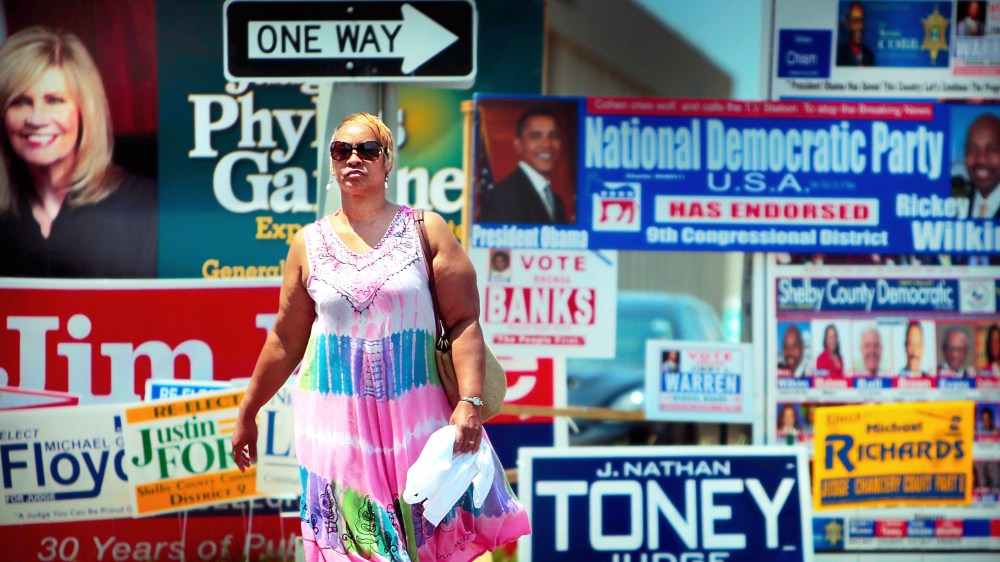 Annette Mallet passes a wall of campaign signs on Poplar Ave. Wednesday, Aug. 6, 2014  near the Shelby County Election Commission Offices in Memphis, Tenn.
