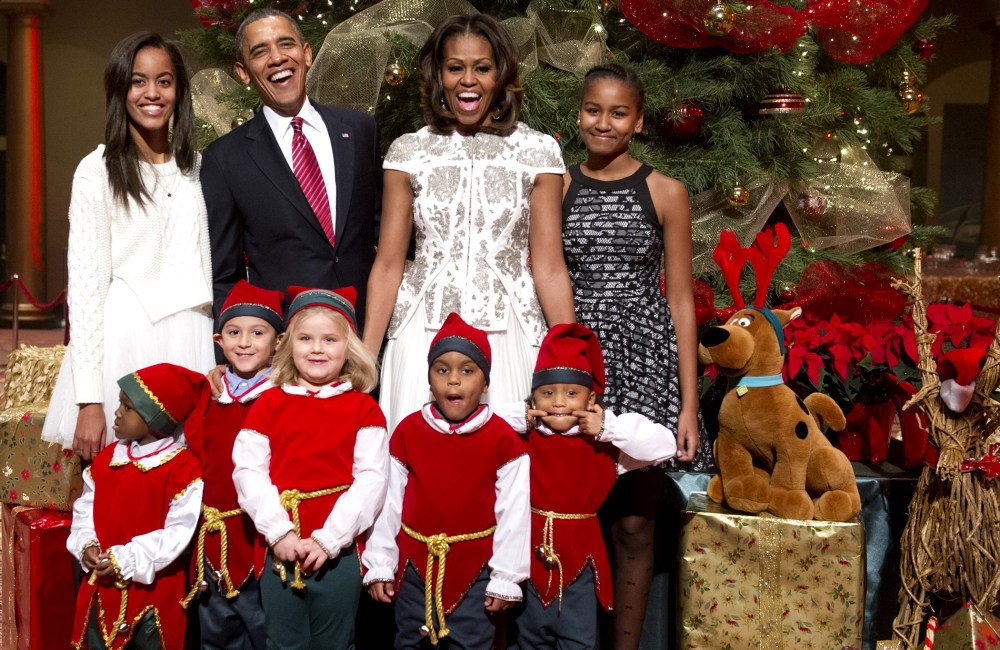 US President Barack Obama, First Lady Michelle Obama and their daughters, Sasha (R) and Malia (L), pose for photographs alongside children dressed as elves in Washington on Dec. 15, 2013.