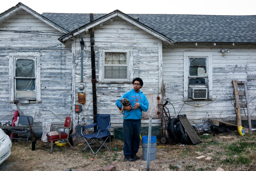 Thomas Blakely standing behind his family’s weather-beaten, clapboard house holding Wicked, a 3-year-old Pug-Shitzu. There’s little to do in his small town. Thomas’s family have done all they can to keep him focused and out of trouble.
