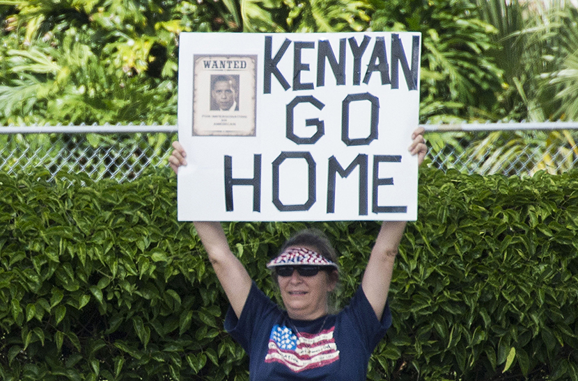 Protesters hold up placards as the president's motorcade passes by in Orlando, Forida, August 10, 2013.  (Photo by Jim Watson/Getty Images)