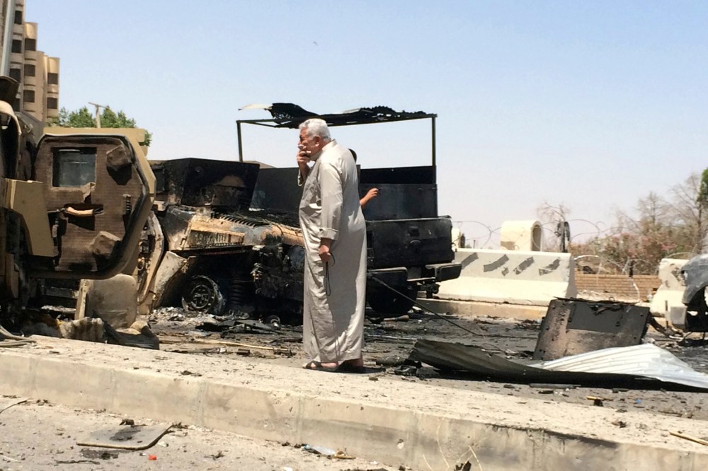 A man looks at burnt vehicles belonging to Iraqi security forces one day after radical Sunni Muslim insurgents seized control of city of Mosul