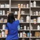 A pharmacy technician grabs a bottle of drugs off a shelf at a pharmacy