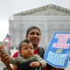 Olga Urbina holds a sign that reads "American Born Children are American Children" as her son Aers holds an American flag.