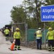 Workers install a sign reading "Alligator Alcatraz" at the entrance to a new migrant detention facility at Dade-Collier Training and Transition facility, Thursday, July 3, 2025, in Ochopee, Fla.