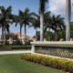 A sign is seen near the entrance to the Trump National Doral golf resort, many palm trees in the background near resort buildings