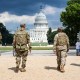 National Guard soldiers walk outside, the U.S. Capitol is seen in the distance