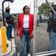 LaMonica McIver walks past a chainlink fence gate outside