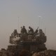 Israeli soldiers sit on top of tank parked