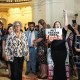 Senfronia Thompson, left, walks past a crowd of people into the House Chamber, a person holds a sign that says "put Texans first"