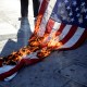 An American flag burns on the ground