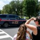 An Immigration and Customs Enforcement police SUV patrols on the road as people watch from the sidewalk
