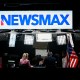 News anchors work at Newsmax's booth.