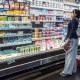 A person looks at products in the dairy aisle of a supermarket