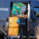 An Amazon Prime delivery person lifts packages while making a stop