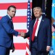 Pete Hegseth, left, shakes hands with Donald Trump on stage