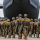 Soldiers walk into an airplane parked on the tarmac outside