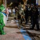 A protester in a frog costume stands in front of a line of federal law enforcement officers outside a United States Immigration and Customs Enforcement (ICE) facility.