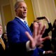 Senate Majority Leader John Thune raises his hand as he speaks to the press.