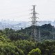High angle view of cityscape with forest area and high voltage electricity pylon.