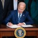 Joe Biden signs an act at the White House.