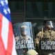 A demonstrator holds an upside down US flag as they face California National Guard.