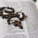 Table top view of a wooden rosary resting on a Bible.