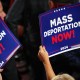 A person holds a sign that reads "Mass Deportation Now" during the third day of the Republican National Convention.