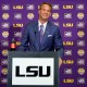 Lane Kiffin stands behind a podium at a press conference at Tiger Stadium in Baton Rouge, L.A.