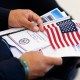 A new US citizen holds a program waiting to take the Oath of Allegiance before receiving their naturalization certificates.
