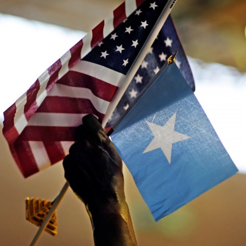 A holds U.S. and Somali flags in Minneapolis, MN.