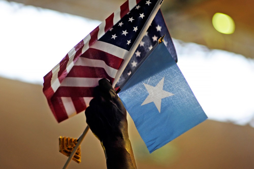 A holds U.S. and Somali flags in Minneapolis, MN.