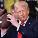 President Donald Trump holds up a football presented to him during a presentation ceremony for the Commander-in-Chief Trophy in the White House on April 15, 2025.