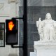 The Contemplation of Justice statue outside the US Supreme Court beside a "Don't Walk" upraised hand symbol in Washington, D.C.