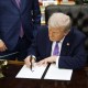 President Donald Trump signs an executive order in the Oval Office.