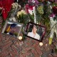 Lit candles and flowers rest by framed photos of mass shooting victims MukhammadAziz Amurzokov and Ella Cook at a memorial near Brown University.