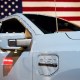 A Ford Motor Co. F-150 Lightning EV in front of an American flag.