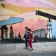 Women walk past a mural depicting an oil pump on April 14, 2021 in a street of Caracas, Venezuela.