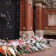 A student stands at the Van Wickle Gates of Brown University after laying down flowers.