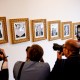 Members of the media take photographs of framed portraits part of the "Presidential Walk of Fame" on the wall of the colonnade outside the Oval Office.