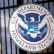 The U.S. Department of Homeland Security seal hangs on a fence at the agency’s headquarters in Washington.