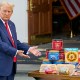 President Donald Trump gestures toward a table of groceries during a news conference.
