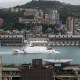 A coast guard ship sails through a body of water surrounded by a city.