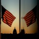 At sunset, an American flag flies in the foreground with the Capitol in focus in the background.