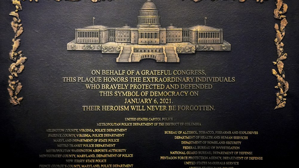 A plaque reads, "On behalf of a grateful Congress, this plaque honors the extraordinary individuals who bravely protected and defended this symbol of democracy on January 6, 2021. Their heroism will never be forgotten."